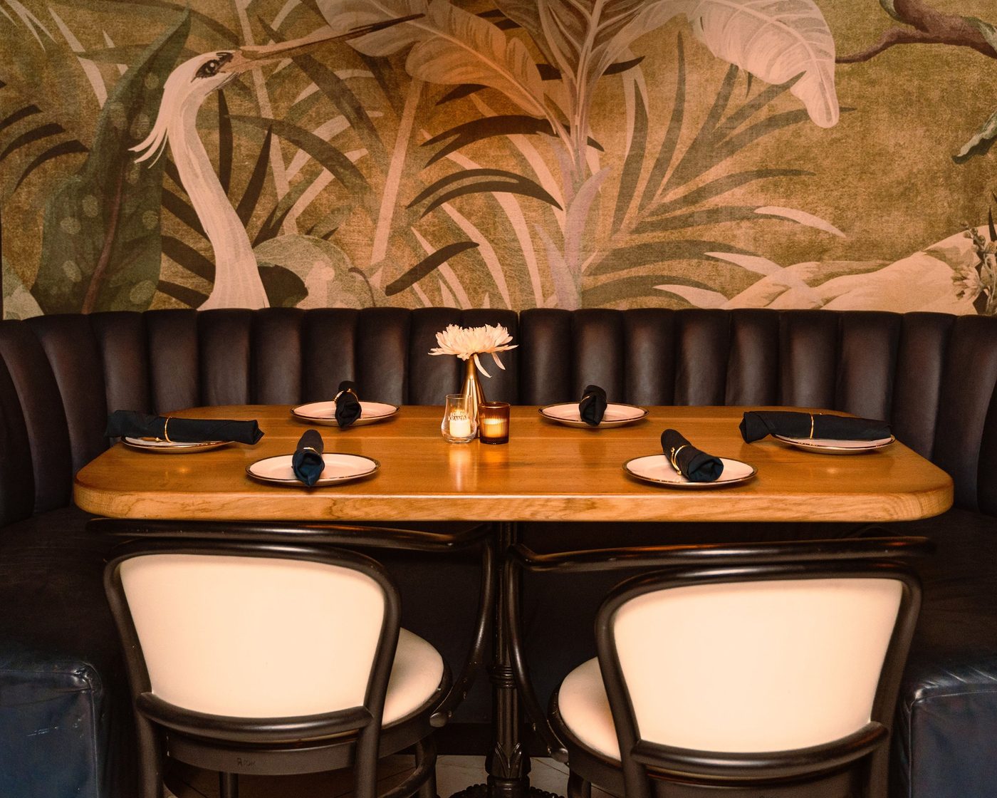 A set table in the channelled leather booth, under the heron mural